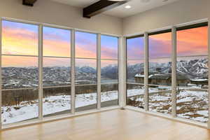 Unfurnished sunroom with a wealth of natural light, a mountain view, and beam ceiling