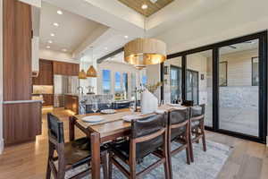 Dining area with a raised ceiling, light wood-type flooring, and recessed lighting