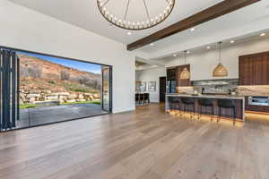 Living room featuring beamed ceiling, light wood finished floors, an inviting chandelier, and recessed lighting