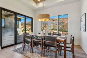 Dining area with a tray ceiling, a wealth of natural light, light wood-type flooring, and baseboards