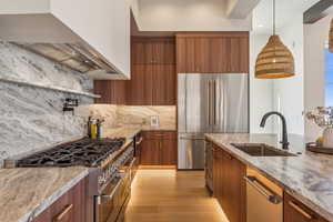 Kitchen featuring wall chimney range hood, stainless steel appliances, a sink, and modern cabinets