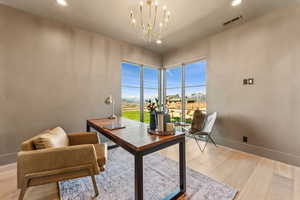 Office area with light wood-style flooring, a notable chandelier, visible vents, baseboards, and recessed lighting