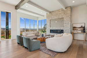 Living area with wood-type flooring, a fireplace, beamed ceiling, and recessed lighting