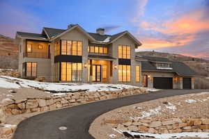 View of front of house with a chimney, a garage, aphalt driveway, and a balcony
