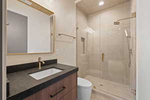 Bathroom with toilet, a stall shower, visible vents, vanity, and recessed lighting
