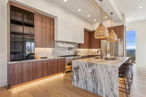 Kitchen with a sink, brown cabinetry, light wood-style flooring, high quality appliances, and modern cabinets