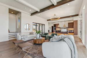 Living room with an inviting chandelier, light wood-type flooring, beamed ceiling, and recessed lighting