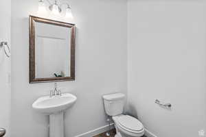 Half bath featuring toilet, baseboards, and wood finished floors