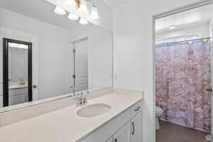 Bathroom featuring toilet, vanity, and a shower with curtain