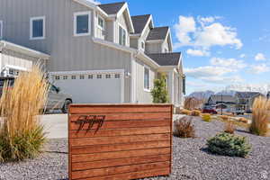 View of home's exterior featuring a mountain view, a residential view, a garage, a shingled roof, and board and batten siding