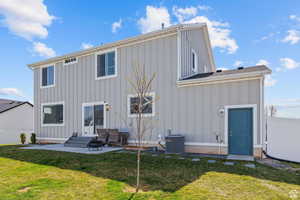 Back of property featuring a lawn, board and batten siding, central air condition unit, and fence