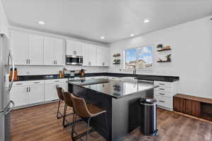 Kitchen featuring stainless steel appliances, tasteful backsplash, a kitchen breakfast bar, open shelves, and a kitchen island