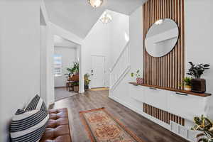 Entrance foyer with stairs, lofted ceiling, wood finished floors, an inviting chandelier, and baseboards