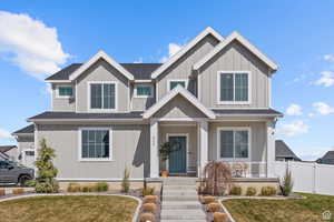 Craftsman house featuring board and batten siding, roof with shingles, a front lawn, and fence