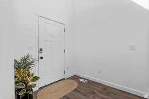 Entryway featuring baseboards, dark wood-style flooring, and visible vents