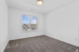 Empty room with carpet floors, baseboards, and visible vents