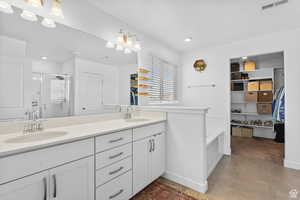 Full bath with a stall shower, visible vents, a sink, and double vanity