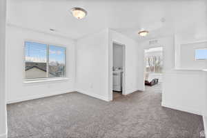Unfurnished bedroom featuring baseboards, washer / dryer, visible vents, and carpet floors
