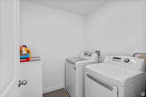 Washroom with laundry area, dark tile patterned flooring, baseboards, and washing machine and dryer