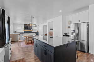 Kitchen featuring stainless steel appliances, dark wood finished floors, a center island, white cabinets, and hanging light fixtures