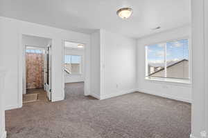 Empty room with carpet, visible vents, and baseboards
