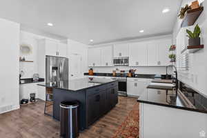 Kitchen with a center island, open shelves, appliances with stainless steel finishes, and a sink