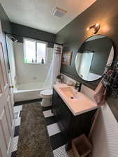 Bathroom with shower / bathtub combination with curtain, toilet, vanity, and a textured ceiling