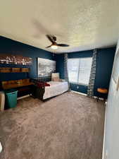 Bedroom with a textured ceiling, carpet, ceiling fan, and baseboards
