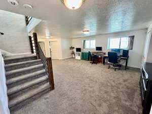 Home office featuring a textured ceiling, carpet, and baseboards