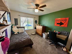 Carpeted bedroom featuring a textured ceiling and ceiling fan