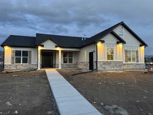 View of front of property with a porch, roof with shingles, stone siding, and board and batten siding