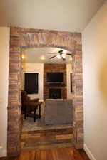 Living area with baseboards, hardwood / wood-style floors, ceiling fan, and a large fireplace