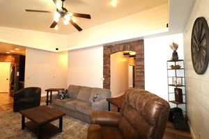 Living room with arched walkways, baseboards, and ceiling fan