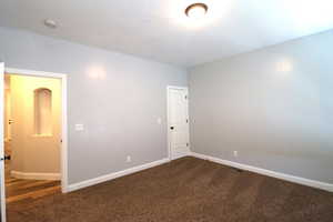 Empty room with dark colored carpet and baseboards
