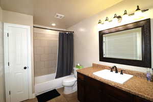 Bathroom featuring shower / bath combo with shower curtain, toilet, visible vents, tile patterned flooring, and vanity