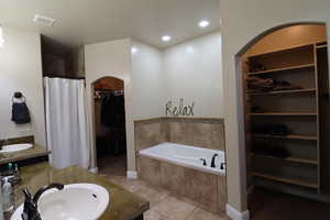 Bathroom featuring a garden tub, visible vents, tile patterned flooring, and a sink