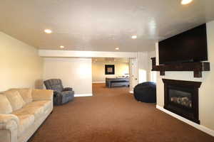 Living room featuring baseboards, carpet floors, a glass covered fireplace, and recessed lighting