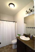 Bathroom with tile patterned floors, toilet, a shower with shower curtain, and vanity