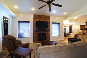 Living area featuring a fireplace, ceiling fan, light wood-style flooring, and baseboards