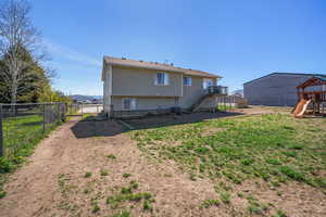 Back of house featuring cooling unit, a playground, a fenced backyard, a yard, and stairs