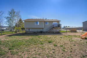 Back of property featuring a lawn, fence, stairs, a deck, and a playground