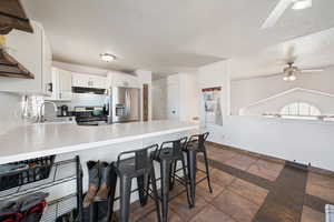 Kitchen featuring a ceiling fan, under cabinet range hood, a sink, a peninsula, and appliances with stainless steel finishes