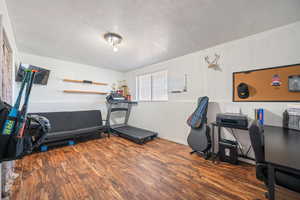 Workout room featuring a textured ceiling, wood finished floors, and baseboards