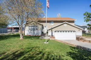 View of front of house with concrete driveway, a front yard, and an attached garage