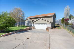 View of front of house with driveway, a mountain view, fence, a garage, and a front lawn