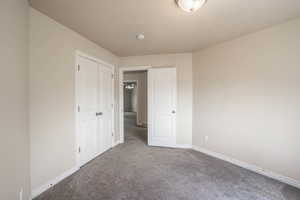 Unfurnished bedroom featuring carpet, baseboards, and a closet