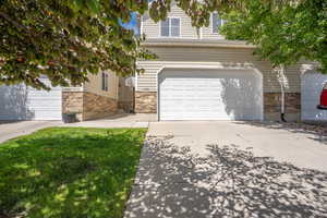 View of front facade featuring an attached garage, stone siding, and driveway
