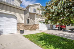 Exterior space with concrete driveway, a garage, and stone siding