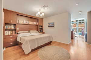 Bedroom with an inviting chandelier, light wood-type flooring, and baseboards