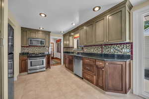 Kitchen featuring stainless steel appliances, a sink, tasteful backsplash and granite counters